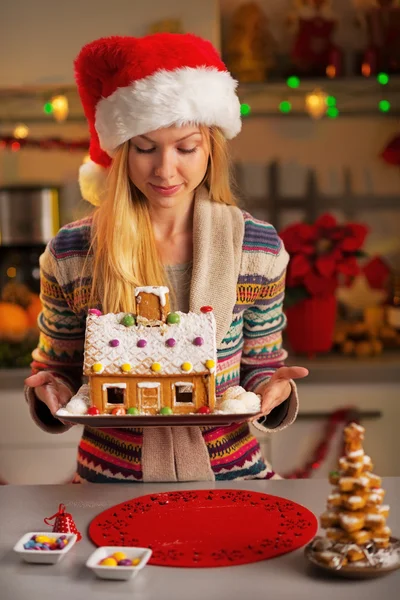 Menina adolescente feliz em santa chapéu segurando casa de biscoito de Natal — Fotografia de Stock