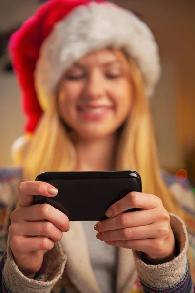 Nahaufnahme auf glückliches Teenager-Mädchen mit Weihnachtsmannhut, das SMS schreibt — Stockfoto