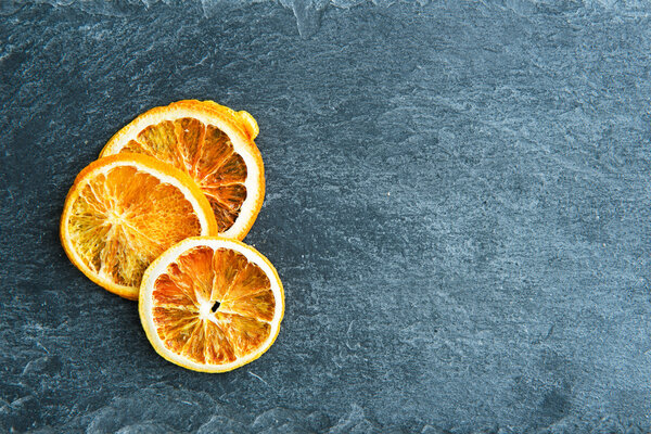 Closeup on dried orange slices on stone substrate
