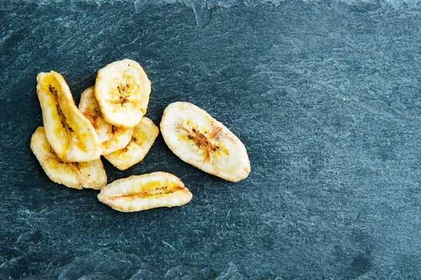 Fechar em chips de banana no substrato de pedra — Fotografia de Stock