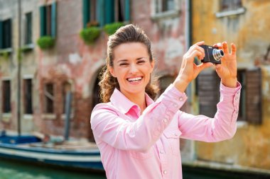 Smiling young woman taking photo in venice, italy clipart