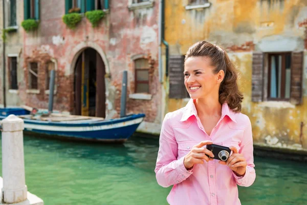 Счастливая молодая женщина с фотокамерой, смотрящая на копировальное пространство, пока — стоковое фото