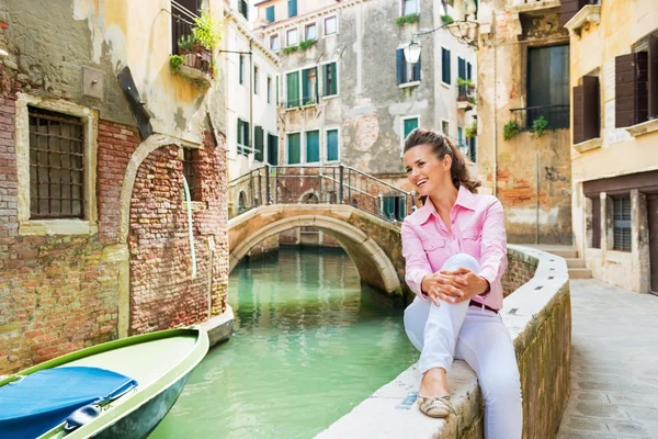 Happy young woman sitting on bridge in venice, italy and looking — Stock Photo, Image