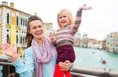 Mutlu anne ve bebek kız ile köprü üzerinde dururken sallayarak