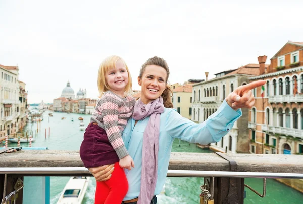 Baby girl and mother poiting while standing on bridge with grand — Stock Photo, Image