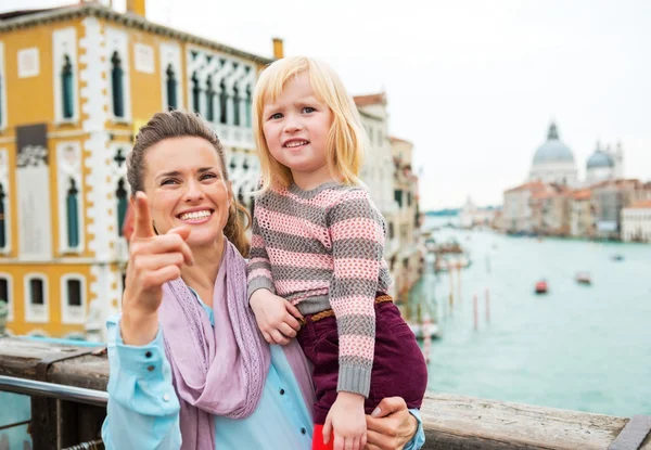 Baby girl and mother poiting while standing on bridge with grand — Stock Photo, Image