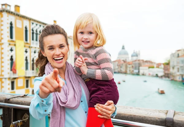 Baby girl and mother poiting in camera while standing on bridge — Stock Photo, Image