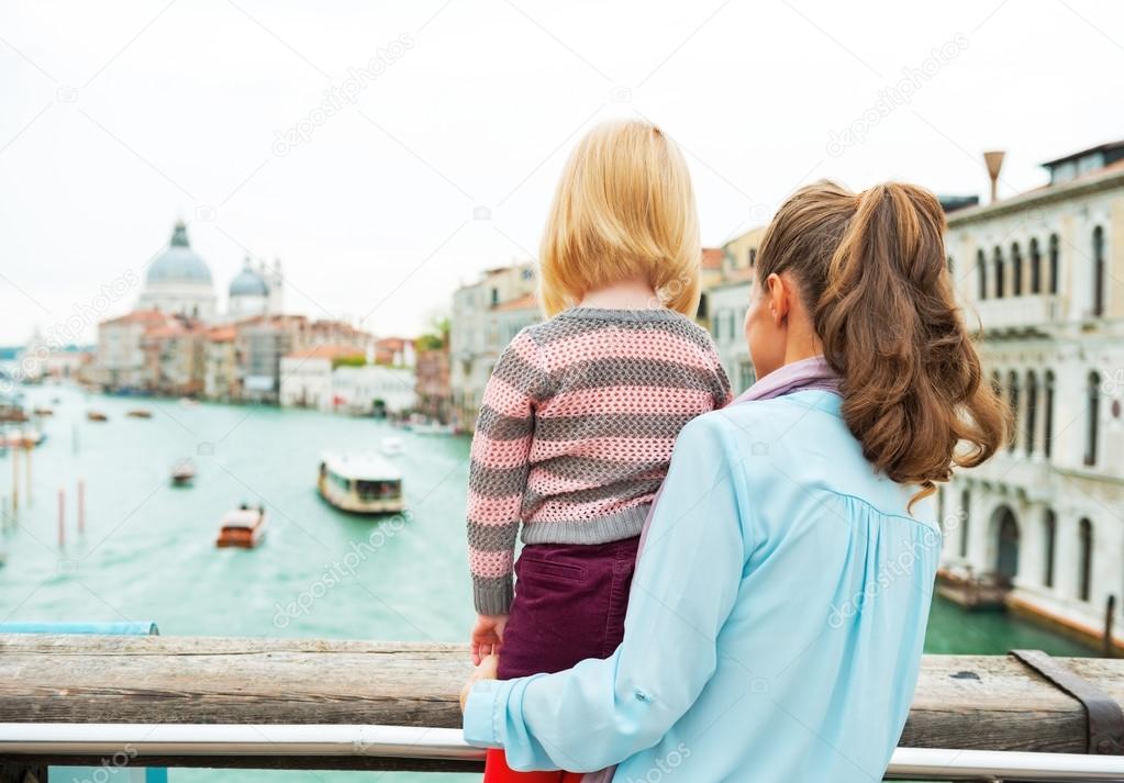 Mother and baby girl standing on bridge with grand canal view in