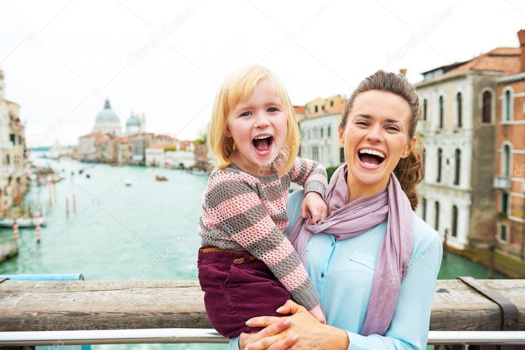 Portrait of happy mother and baby girl standing on bridge with g