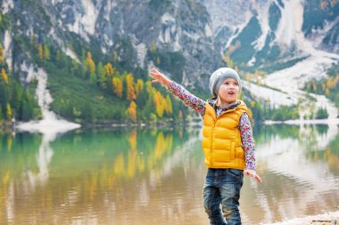 Child pointing on copy space while on lake braies in south tyrol clipart