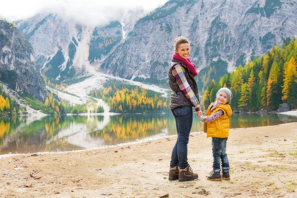 Fuld længde portræt af glad mor og baby på søen braies i - Stock-foto