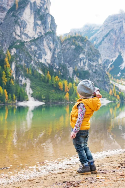Child throwing stones while on lake braies in south tyrol, italy