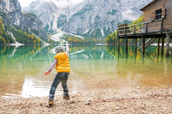 Criança atirando pedras em braies lago no sul do tirol, itália. retaguarda — Fotografia de Stock