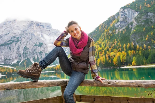 Portrait of happy young woman sitting while on lake braies in so — Stock Photo, Image