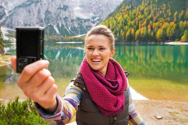 Usměvavá mladá žena s vlastní fotografií na jezeře braies v Jižní ty — Stock fotografie