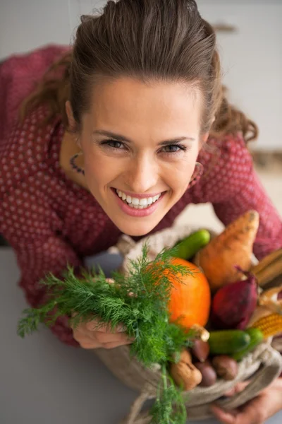 Porträtt av glad ung hemmafru med shopping påse med färska grönsaker — Stockfoto