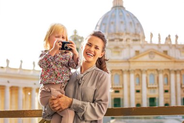 Mutlu anne ve bebek kız piazza san pietr üzerinde fotoğraf makinesi ile