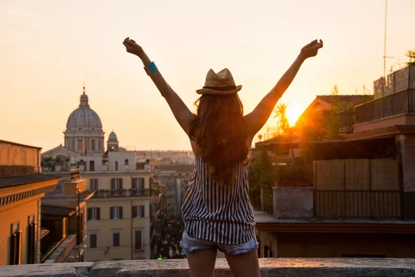 Молодая женщина смотрит на крыши Рима на закате и радуется . — стоковое фото