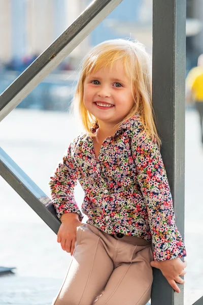 Portrait of happy baby girl sitting on street — Stock Photo, Image