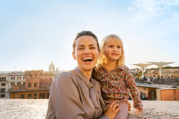 Retrato de mãe feliz e bebê menina na rua com vista para roo — Fotografia de Stock