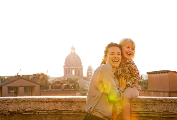 Portrait of smiling mother and baby girl on street overlooking r