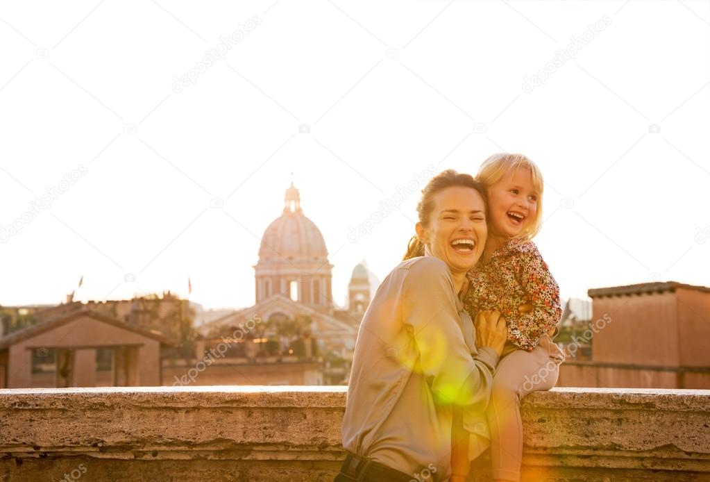 Portrait of smiling mother and baby girl on street overlooking r