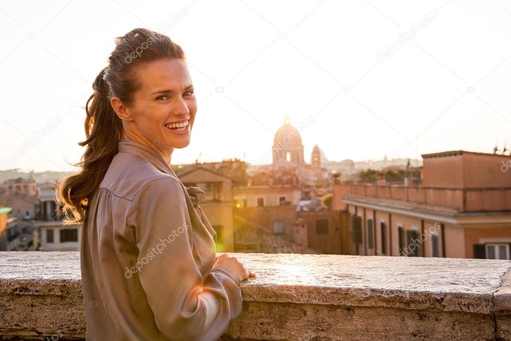 Young woman standing on street overlooking rooftops of rome on s