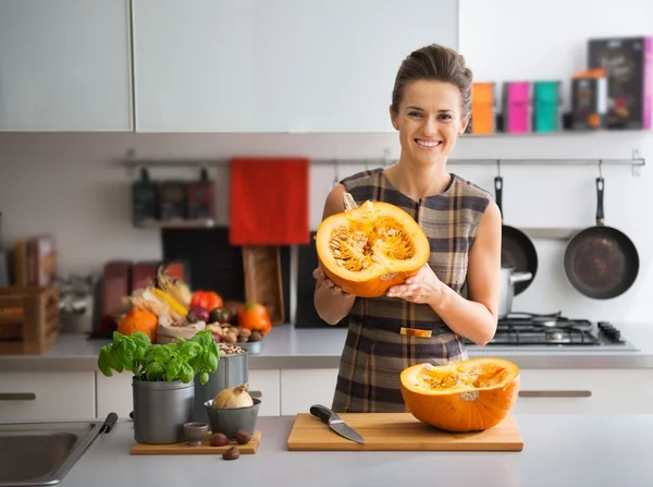 Портрет счастливой молодой домохозяйки на кухне с тыквой — стоковое фото
