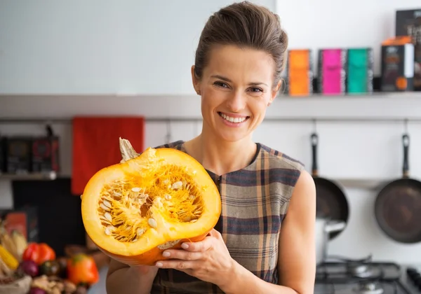 Portrait of happy young housewife showing half of pumpkin — 图库照片