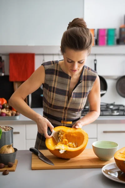 Young housewife removing filling from pumpkin — Stock Photo, Image