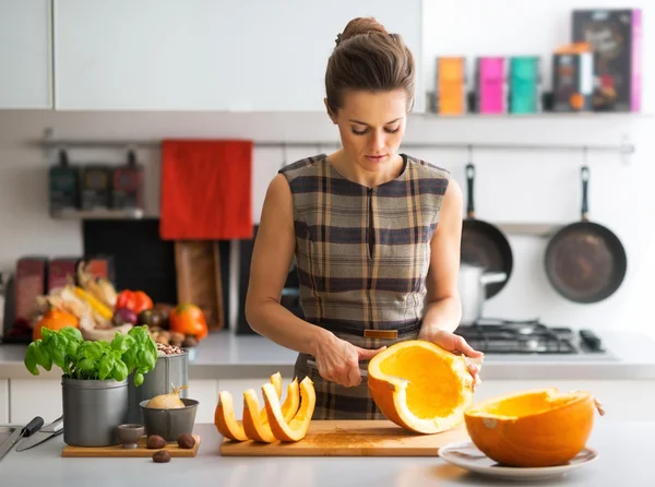 Junge Hausfrau schneidet Kürbis in Küche — Stockfoto