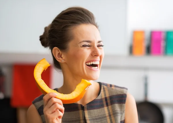 Souriant jeune femme au foyer en utilisant la tranche de citrouille comme combiné téléphonique — Photo