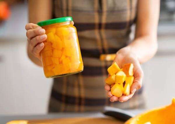 Closeup on young housewife showing jar of pickled pumpkin and pu — Stock Photo, Image