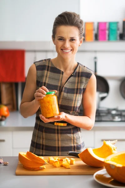 Porträt einer glücklichen jungen Hausfrau, die ein Glas mit eingelegtem Kürbis zeigt — Stockfoto