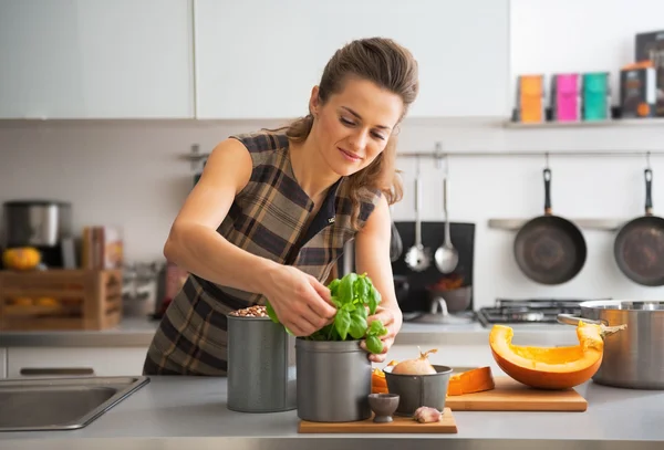Feliz joven ama de casa usando albahaca fresca mientras cocina en la cocina —  Fotos de Stock