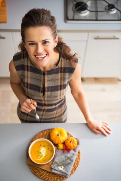 Портрет счастливой молодой домохозяйки, поедающей тыквенный суп — стоковое фото