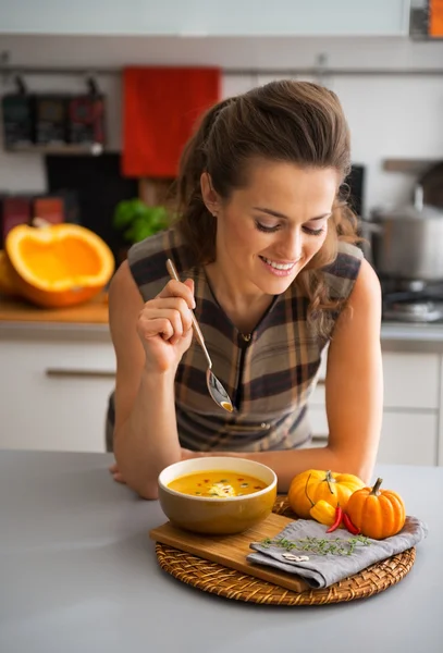 Jonge huisvrouw Pompoensoep eten in keuken — Stockfoto