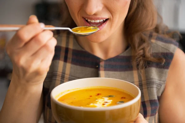 Primer plano de la mujer joven comiendo sopa de calabaza en la cocina —  Fotos de Stock