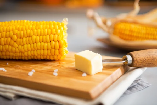 Fechar em milho cozido e manteiga na tábua de corte — Fotografia de Stock