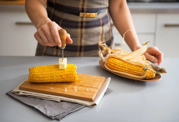 Closeup on young housewife rubbing boiled corn with butter — Stock Photo, Image