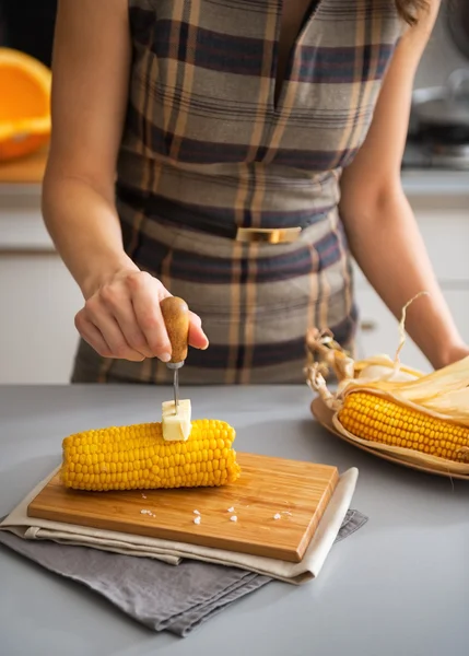 Closeup on young housewife rubbing boiled corn with butter — Stock Photo, Image