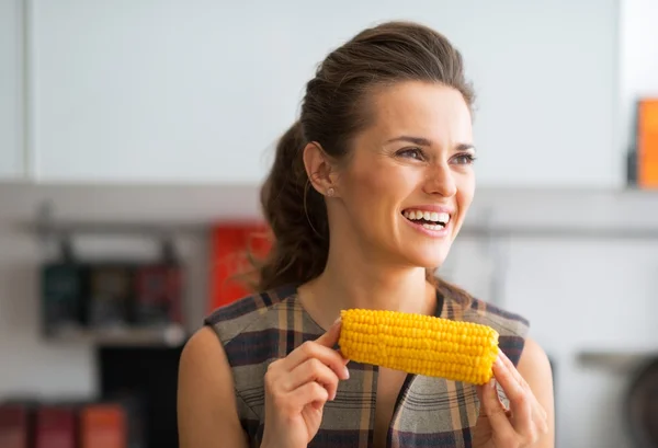 Retrato de feliz ama de casa joven comiendo maíz hervido — Foto de Stock