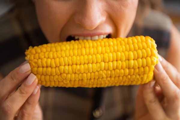 Крупным планом молодая домохозяйка ест вареную кукурузу — стоковое фото