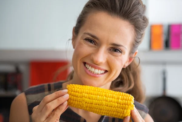 Retrato de una joven comiendo maíz hervido en la cocina — Foto de Stock