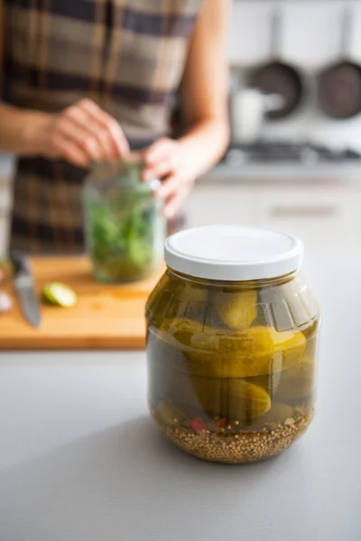 Closeup on jar of marinated cucumbers on table and housewife pic — Stock Image Closeup on jar of marinated cucumbers on table and housewife pic Stock Picture
