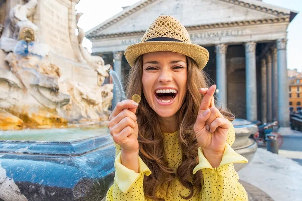 Jovem feliz com dedos cruzados e moeda perto da fonte de — Fotografia de Stock