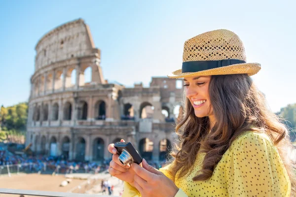 Happy young woman checking photos in camera in front of colosseu — Stock Photo, Image