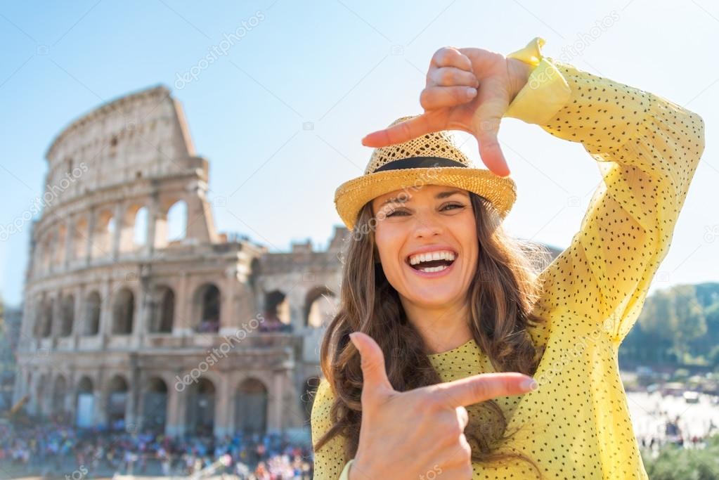 Happy young woman framing in front of colosseum in rome, italy