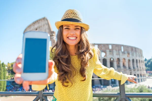 Happy young woman showing cell phone in front of colosseum in ro — Stock Photo, Image