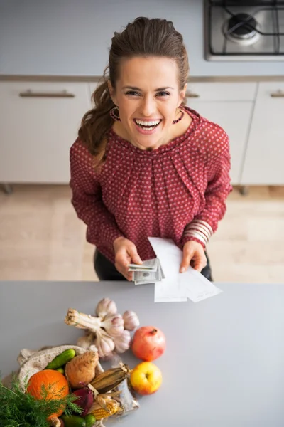 Happy young housewife with money and grocery shopping checks aft — Stock Photo, Image